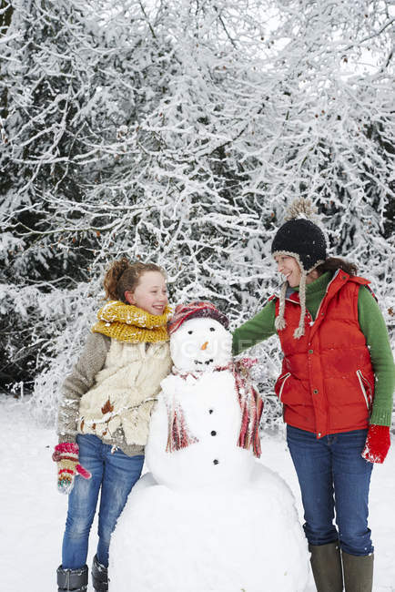 Caucasian happy mother and daughter with snowman — Stock Photo