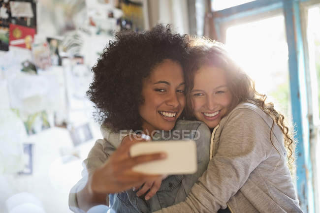 Mujeres tomando fotos juntas en el dormitorio - foto de stock