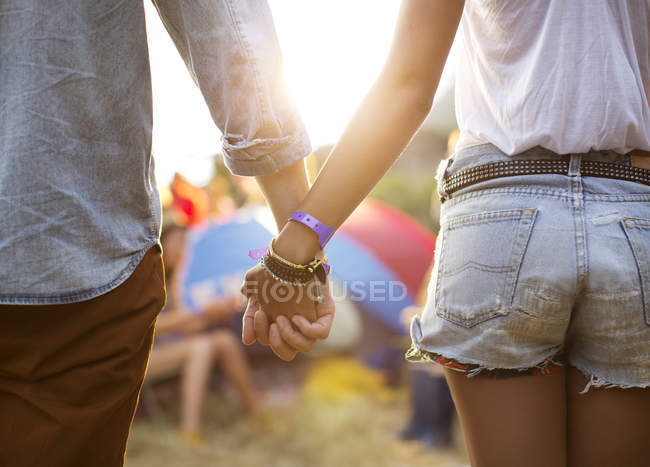 Casal de mãos dadas perto de tendas no festival de música — Fotografia de Stock