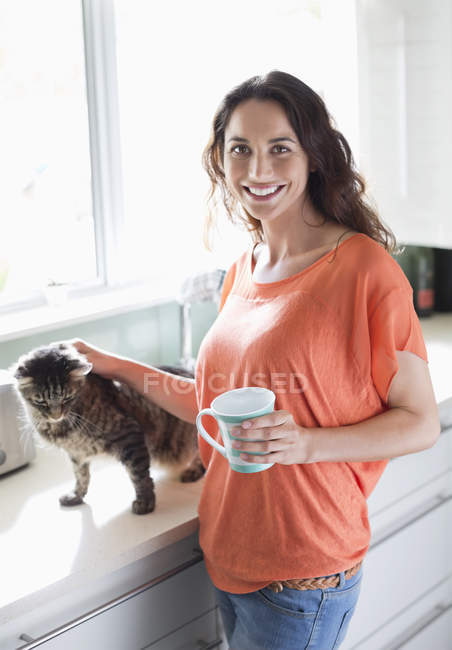 Feliz mulher de estimação bonito gato na cozinha — Fotografia de Stock