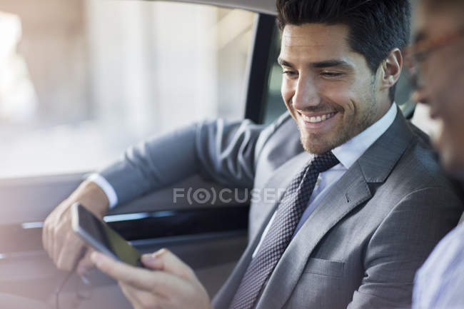Uomini d'affari che guardano il cellulare in macchina — Foto stock