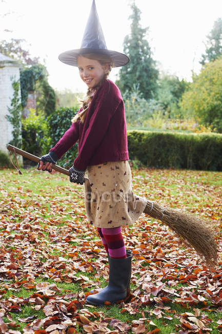 Mädchen trägt Hexenkostüm auf Besen im Freien — Stockfoto