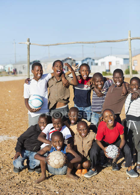 Африканські хлопчики тримають футбольні м'ячі в ґрунтовому полі — стокове фото