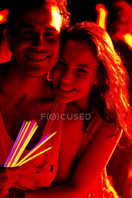 Close up portrait of happy couple with glow sticks at music festival — Stock Photo
