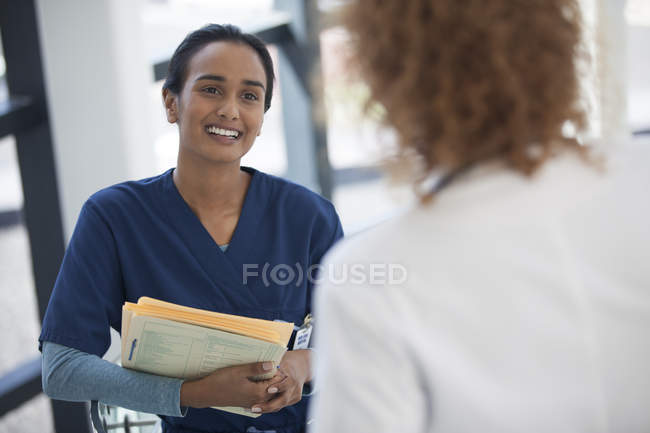 Enfermera y médico moderno hablando en el hospital - foto de stock