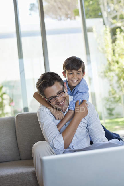 Padre e figlio che utilizzano il computer portatile sul divano — Foto stock