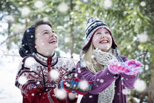 Happy caucasian siblings catching snow together — Stock Photo
