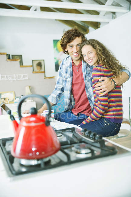 Jeune couple heureux câlin dans la cuisine — Photo de stock