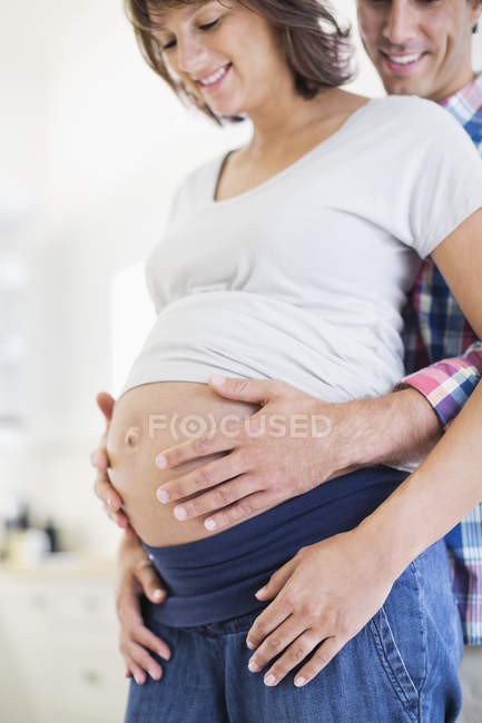 Homem segurando grávida namoradas barriga — Fotografia de Stock
