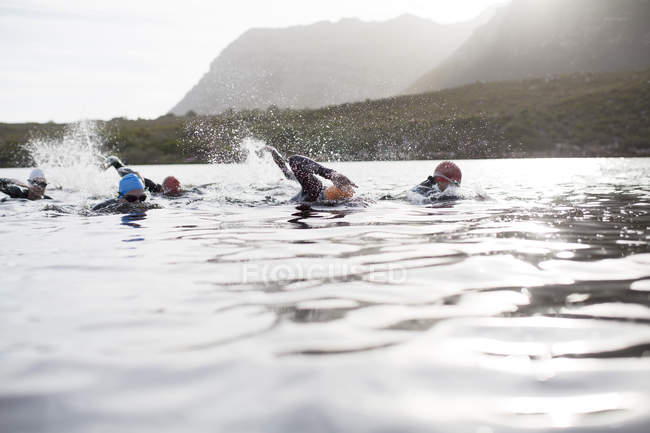 Confident and strong triathletes swimming in river — Stock Photo