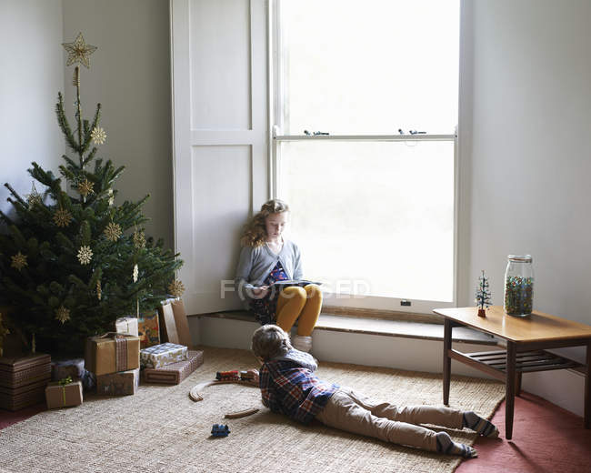Caucasien heureux enfants détente par arbre de Noël — Photo de stock