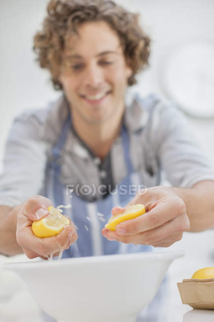 Homme serrant des citrons dans la cuisine — Photo de stock