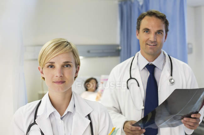 Doctors standing in hospital room and looking at camera — Stock Photo