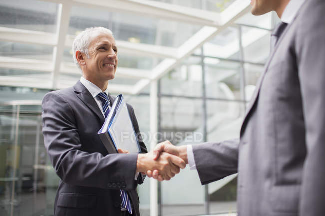 Des hommes d'affaires se serrent la main dans un immeuble de bureaux — Photo de stock