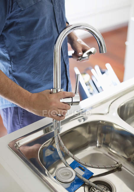 Обрезанное изображение сантехника, работающего на кухонной раковине — стоковое фото
