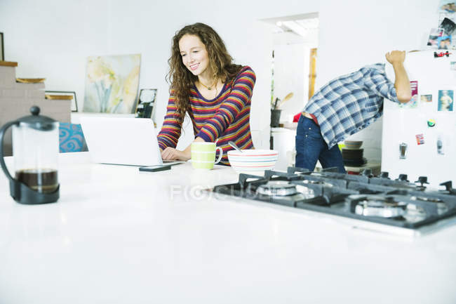 Mujer feliz joven usando el ordenador portátil en el desayuno - foto de stock