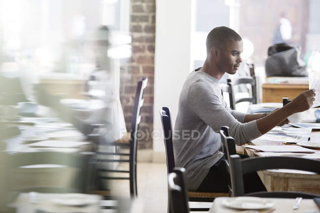 Empresario mirando a través de documentos en la cafetería - foto de stock