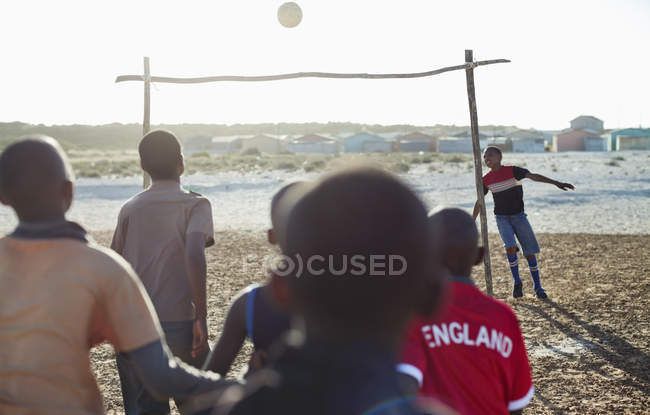 Африканские мальчики вместе играют в футбол на грязном поле — стоковое фото