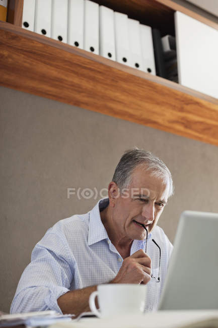 Older man working at desk — Stock Photo