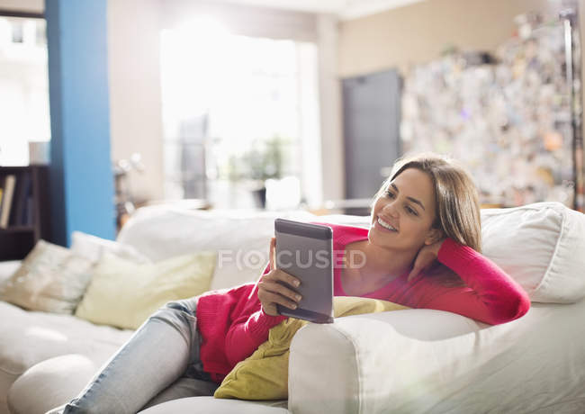 Woman using digital tablet on sofa — Stock Photo