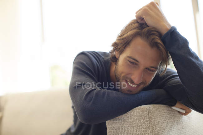 Junger attraktiver Mann lehnt sich auf Arm des Sofas — Stockfoto