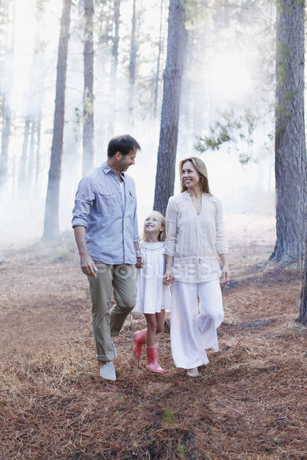 Happy family holding hands and walking in woods — Stock Photo