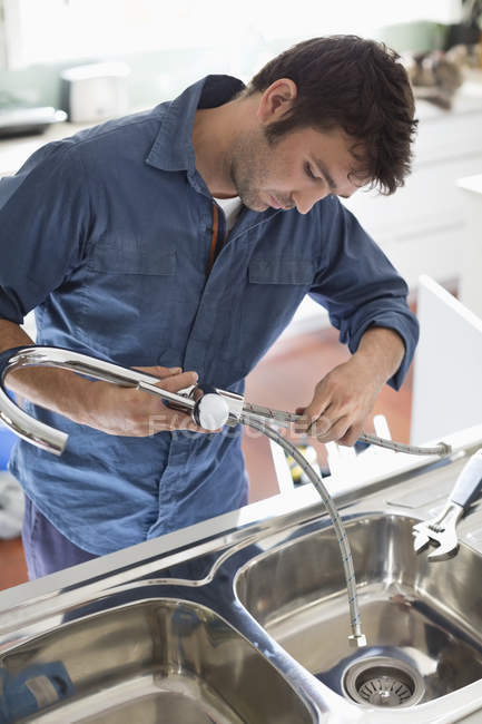 Abile idraulico caucasico che lavora sul lavello della cucina — Foto stock