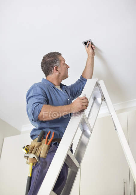 Eletricista caucasiano hábil trabalhando em luzes de teto — Fotografia de Stock