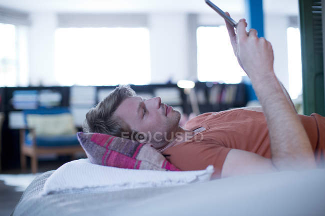 Людина використовує цифровий планшет на ліжку — стокове фото