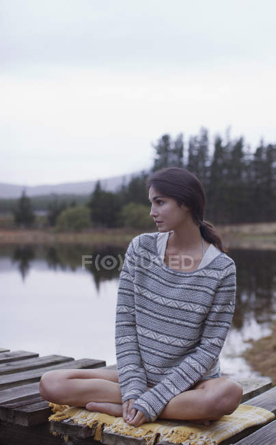 Mulher pensativa sentada na doca no lago — Fotografia de Stock
