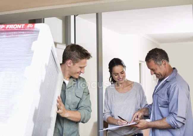 Woman signing for delivery at front door — Stock Photo