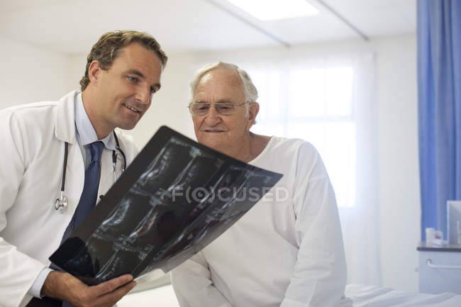 Médico e paciente examinando raios-X no quarto do hospital — Fotografia de Stock