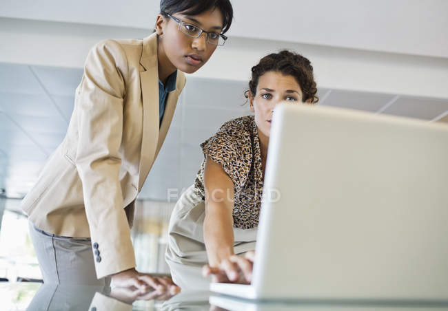 Le donne d'affari che usano il computer portatile insieme in ufficio moderno — Foto stock