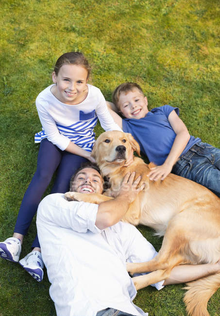 Сім'я відпочиває разом з собакою на газоні — стокове фото