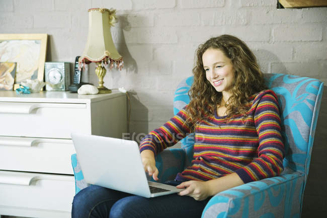 Junge Frau benutzt Laptop im Sessel — Stockfoto