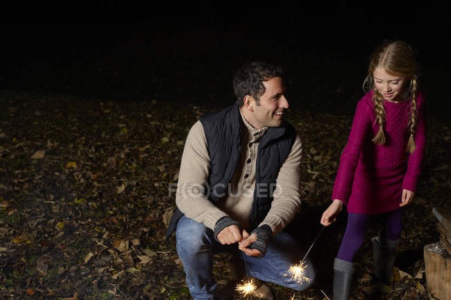 Father and daughter playing with sparklers — Stock Photo