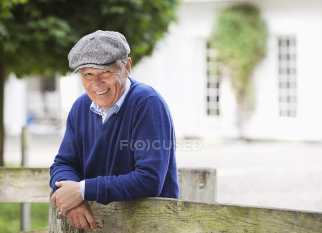 Hombre sonriendo por valla de madera - foto de stock