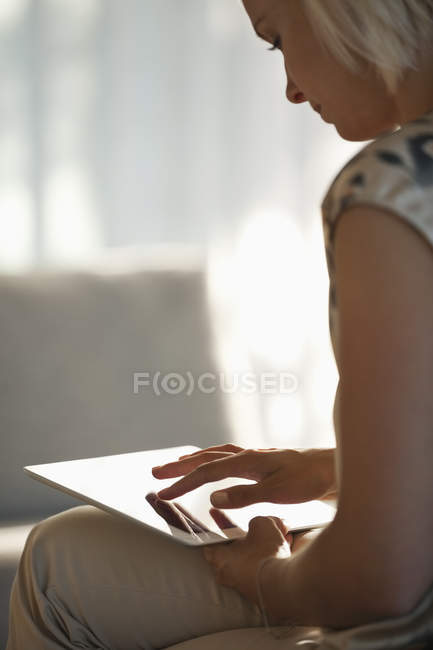 Mujer usando tableta en el sofá - foto de stock