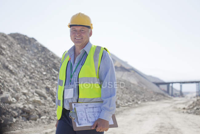 Businessman carrying clipboard in quarry — Stock Photo