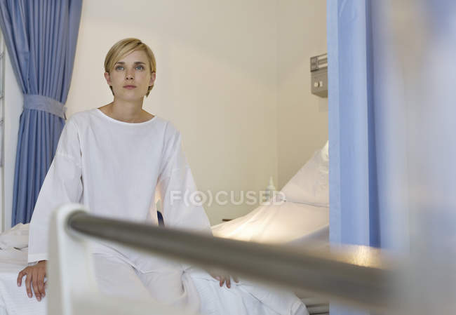 Paciente sentado en una cama de hospital moderna - foto de stock