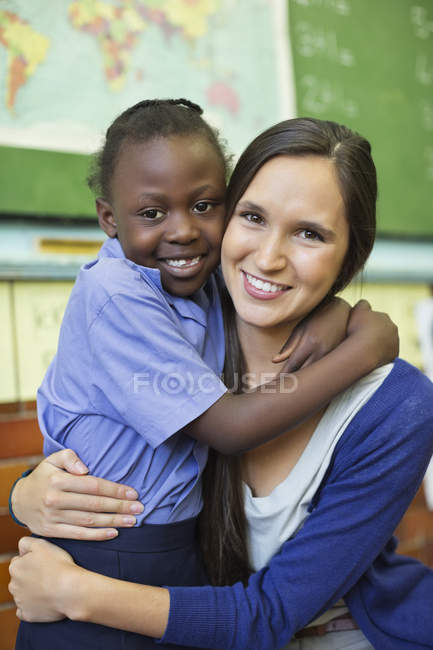 Profesor y estudiante afroamericano abrazándose en clase - foto de stock