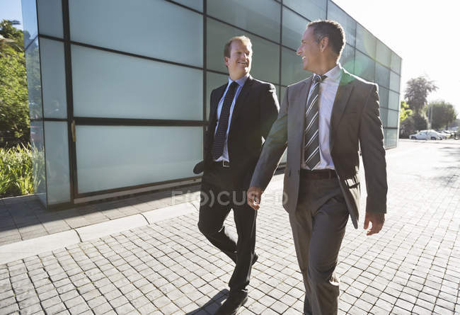 Businessmen talking on city street beside modern office — Stock Photo