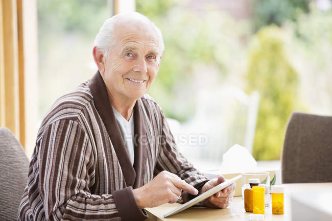 Пожилой человек за столом за планшетом — стоковое фото