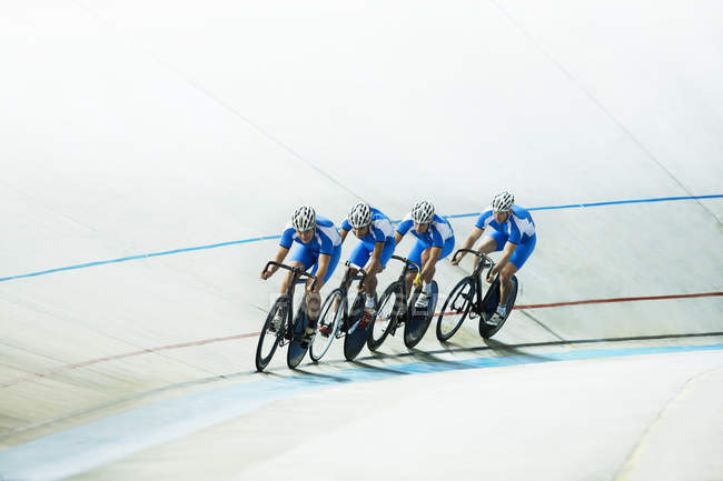 Track cyclists riding in velodrome — Stock Photo
