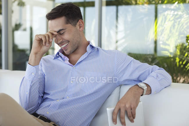 Бизнесмен улыбается на диване в современном офисе — стоковое фото