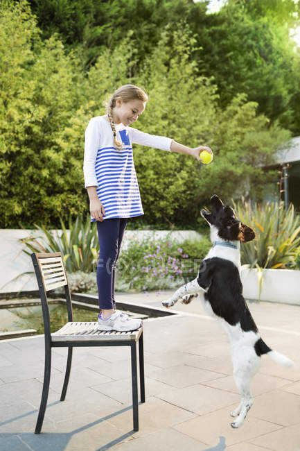 Милая девушка играет с собакой на открытом воздухе — стоковое фото