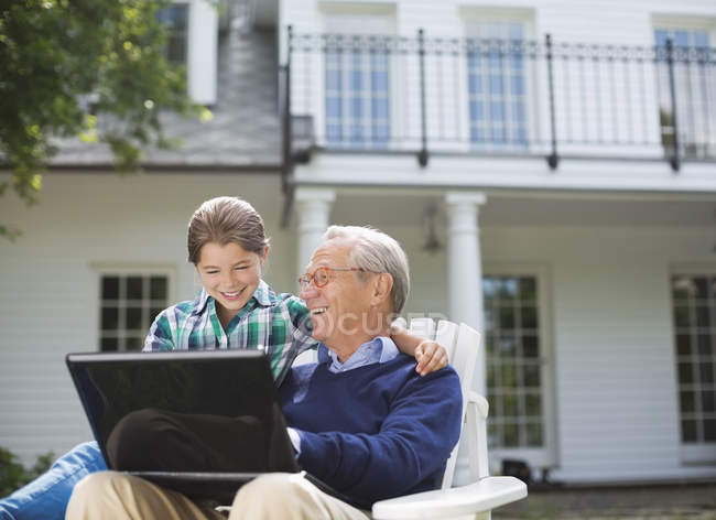Чоловік використовує ноутбук з онукою на відкритому повітрі — стокове фото