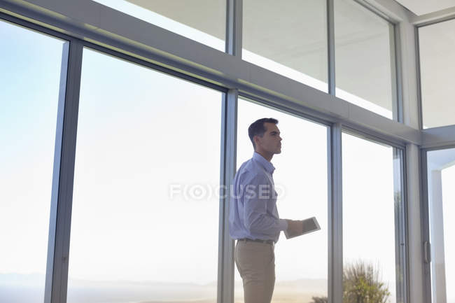 Homme d'affaires utilisant un ordinateur tablette à la fenêtre — Photo de stock
