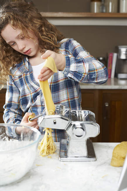 Девушка катит тесто для макарон на кухне — стоковое фото