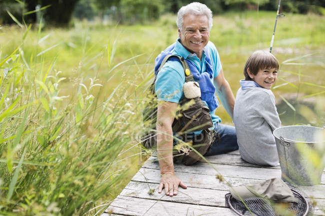 Человек рыбачит с внуком на деревянном причале — стоковое фото